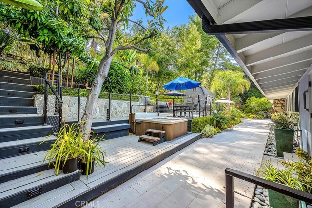 view of patio with a hot tub, fence, stairway, and a wooden deck