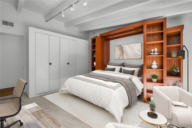 bedroom featuring light carpet, rail lighting, beamed ceiling, visible vents, and a closet