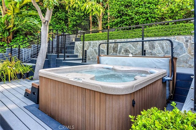 deck featuring a hot tub and fence