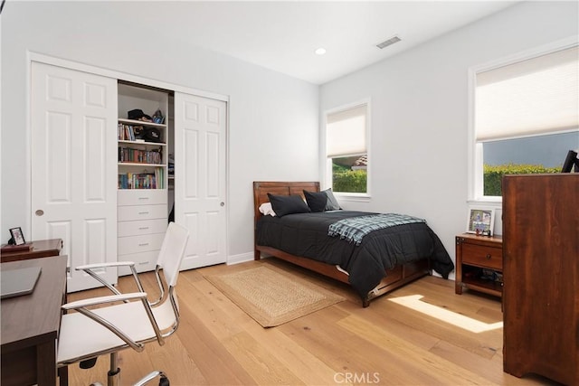 bedroom with a closet, recessed lighting, wood finished floors, and visible vents