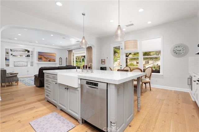 kitchen with a sink, light countertops, arched walkways, recessed lighting, and stainless steel dishwasher