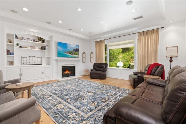 living area featuring visible vents, ornamental molding, and light wood finished floors
