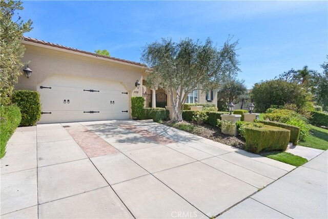 view of front of house featuring a garage, stucco siding, concrete driveway, and a tiled roof