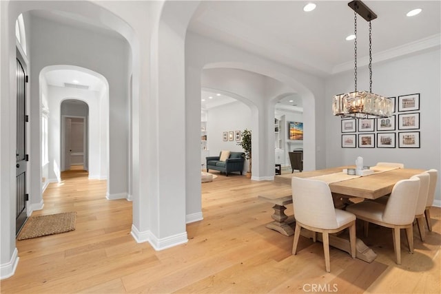 dining room with light wood-style floors, arched walkways, baseboards, and recessed lighting