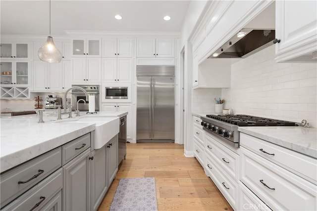 kitchen with built in appliances, white cabinetry, tasteful backsplash, gray cabinetry, and glass insert cabinets