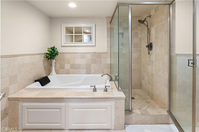 bathroom with recessed lighting, a bath, and a shower stall