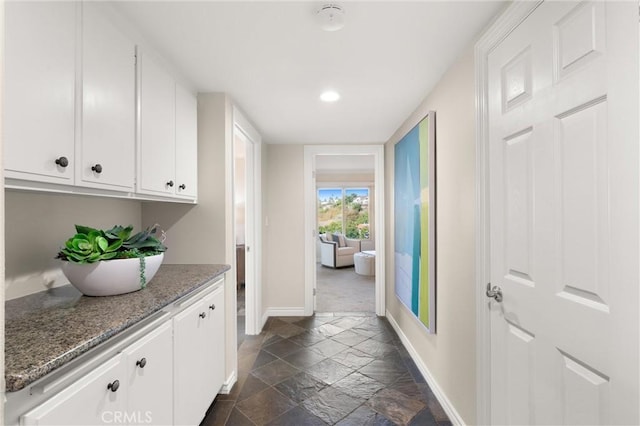 hall featuring baseboards, recessed lighting, and stone tile flooring