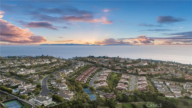 aerial view at dusk with a water view and a residential view