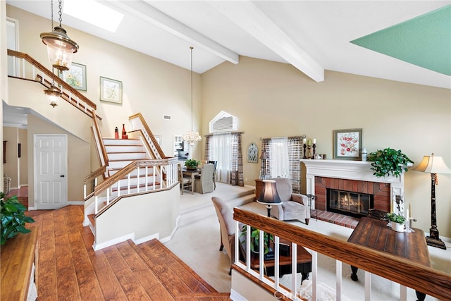 living area featuring stairs, a brick fireplace, hardwood / wood-style floors, beamed ceiling, and high vaulted ceiling