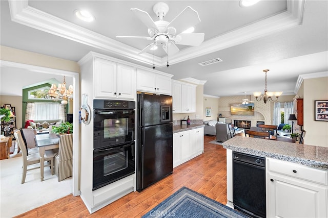 kitchen with visible vents, a raised ceiling, crown molding, and black appliances