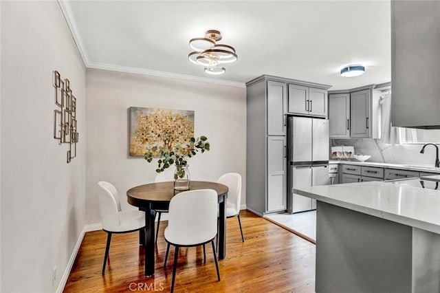 kitchen with freestanding refrigerator, backsplash, gray cabinetry, and light wood-type flooring