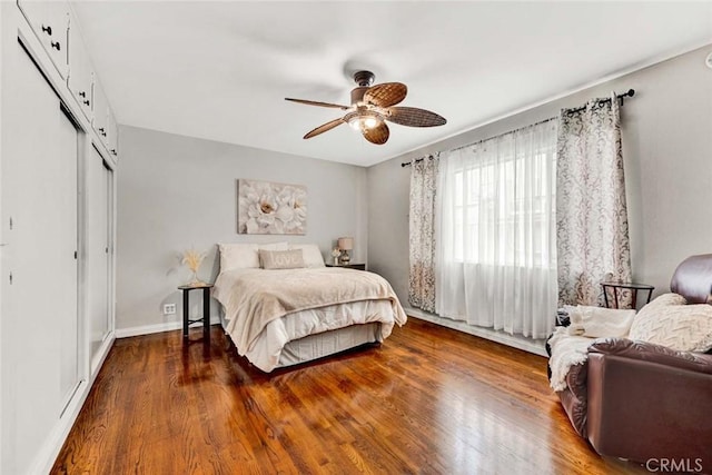 bedroom featuring a closet, baseboards, ceiling fan, and wood finished floors