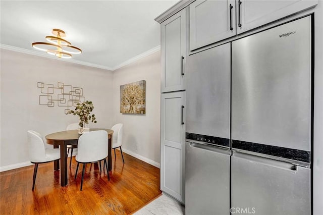interior space with light wood-style floors, gray cabinetry, baseboards, stainless steel fridge, and ornamental molding