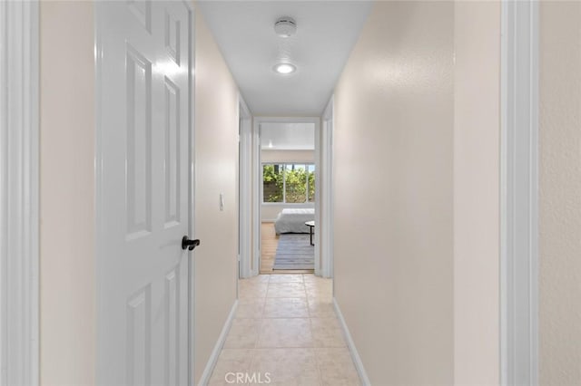 corridor featuring light tile patterned flooring and baseboards