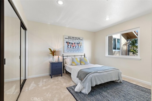 bedroom featuring recessed lighting, baseboards, light carpet, and a closet