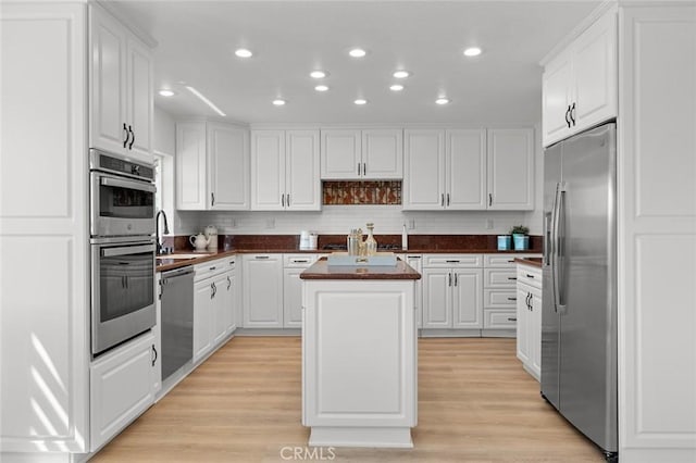 kitchen featuring dark countertops, a center island, white cabinets, stainless steel appliances, and recessed lighting