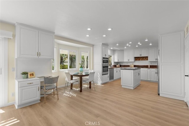 kitchen with recessed lighting, light wood-type flooring, white cabinets, and a center island