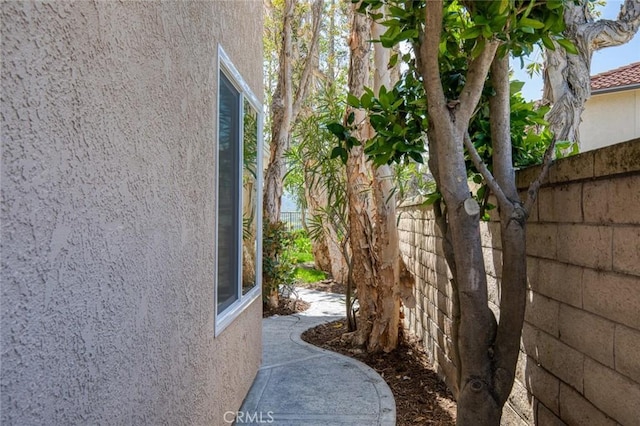 view of side of property featuring stucco siding and fence