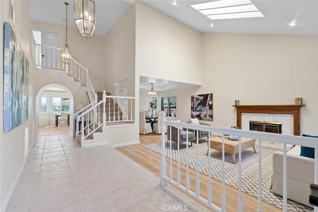 living room with an inviting chandelier, arched walkways, high vaulted ceiling, stairs, and a wealth of natural light
