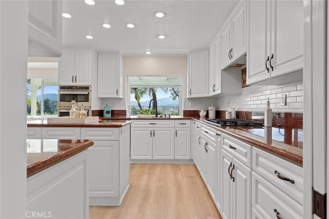 kitchen featuring a sink, appliances with stainless steel finishes, decorative backsplash, and white cabinetry