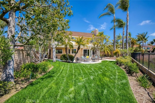 back of property featuring a tiled roof, a chimney, a lawn, a patio area, and a fenced backyard