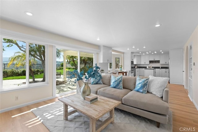 living area featuring recessed lighting, baseboards, and light wood-type flooring