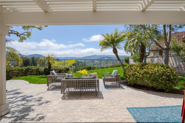 view of patio featuring outdoor lounge area, a mountain view, fence, and a pergola