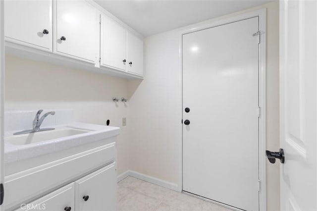 washroom featuring cabinet space, a sink, hookup for a washing machine, baseboards, and light tile patterned floors