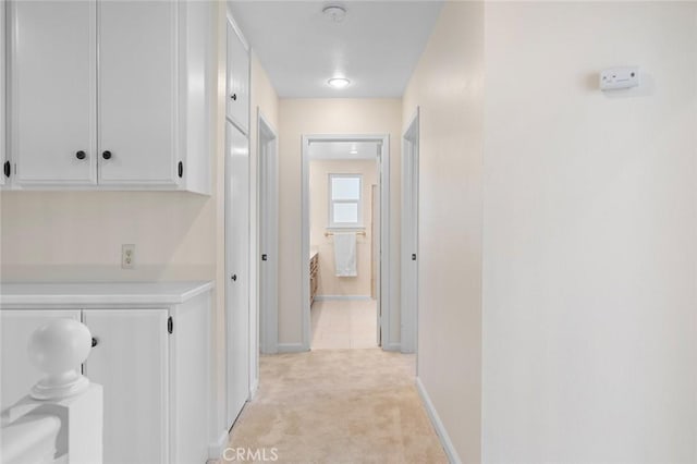 hall with light colored carpet and baseboards