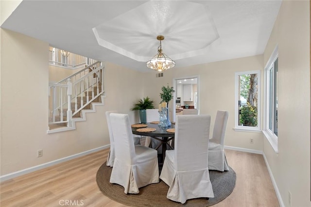 dining room with visible vents, baseboards, stairway, light wood finished floors, and a notable chandelier