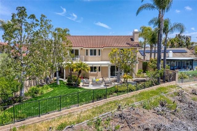 back of house featuring a chimney, a fenced backyard, a patio area, and stucco siding