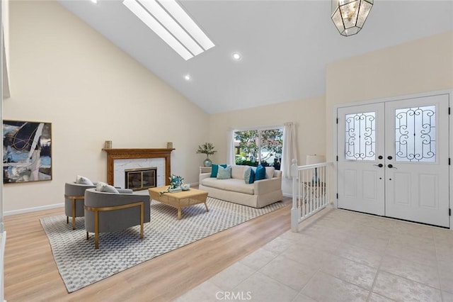 interior space featuring a premium fireplace, high vaulted ceiling, recessed lighting, baseboards, and a skylight