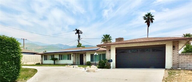 3915 Valencia Ave, San Bernardino, CA 92404 - ranch-style house featuring a garage, solar panels, a mountain view, and concrete driveway