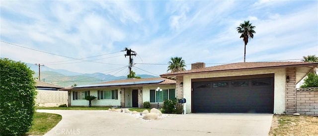 3915 Valencia Ave, San Bernardino, CA 92404 - ranch-style home featuring an attached garage, roof mounted solar panels, a mountain view, and driveway