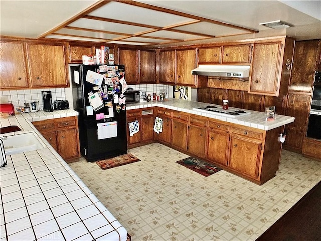 3915 Valencia Ave, San Bernardino, CA 92404 - kitchen featuring tile countertops, under cabinet range hood, black appliances, and brown cabinets
