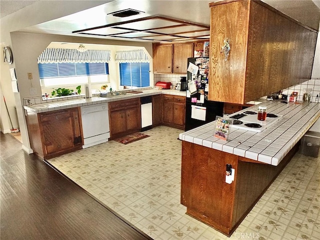 3915 Valencia Ave, San Bernardino, CA 92404 - kitchen with a peninsula, brown cabinets, tile countertops, and white appliances