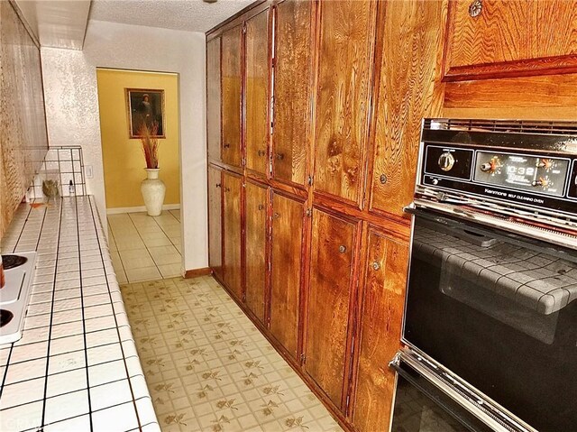 3915 Valencia Ave, San Bernardino, CA 92404 - kitchen with a textured ceiling, brown cabinets, and oven