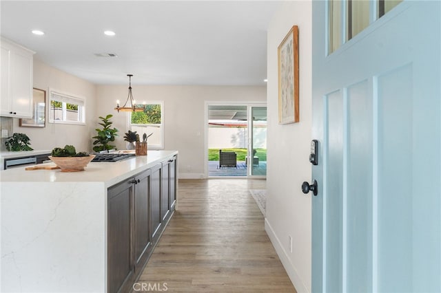 kitchen featuring white cabinets, light wood finished floors, recessed lighting, baseboards, and a kitchen island