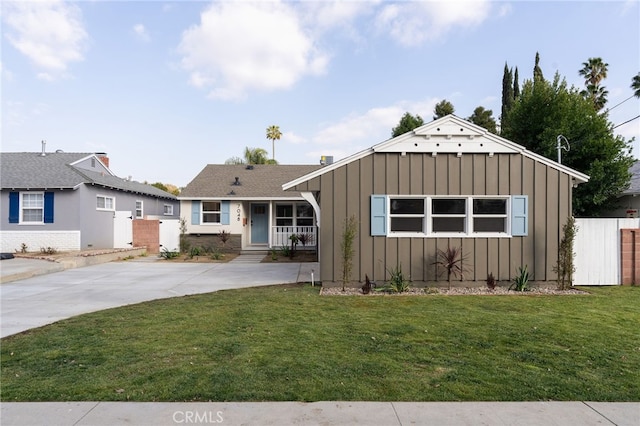 view of front of house featuring fence, board and batten siding, and a front lawn