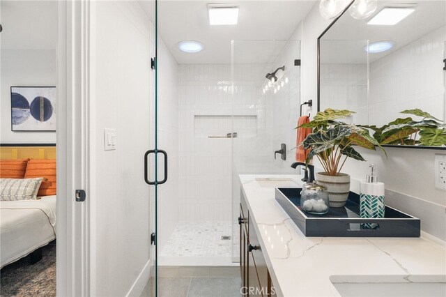 full bathroom featuring double vanity, connected bathroom, tile patterned floors, a shower stall, and a sink
