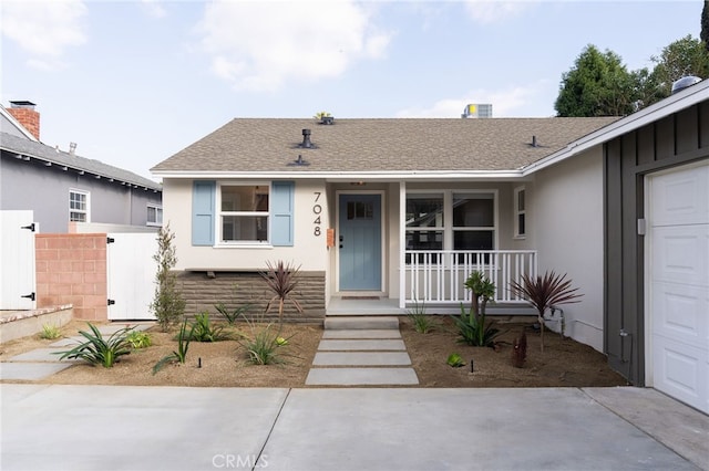 view of front of property with fence, covered porch, a shingled roof, and stucco siding
