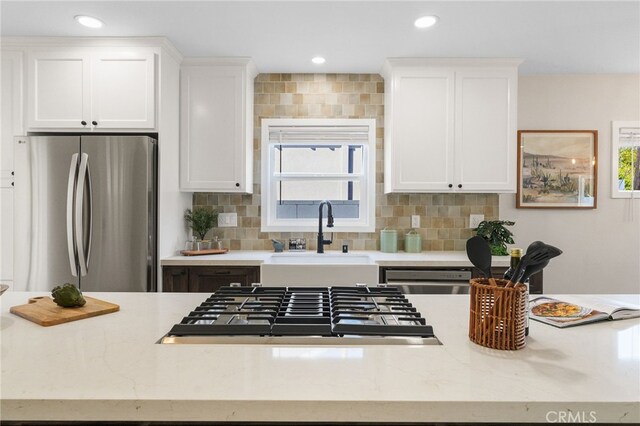 kitchen featuring white cabinets, stainless steel appliances, a sink, and backsplash