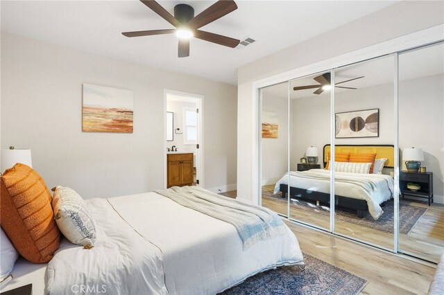 bedroom with visible vents, a closet, wood finished floors, a ceiling fan, and ensuite bath