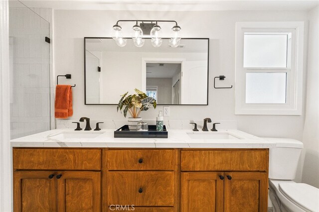bathroom with a sink, toilet, and double vanity