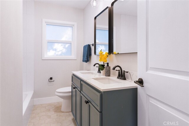bathroom with double vanity, a sink, baseboards, and toilet