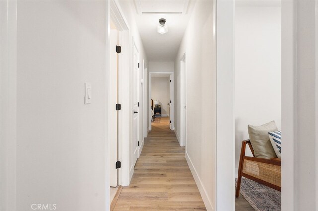hallway with light wood-type flooring and baseboards