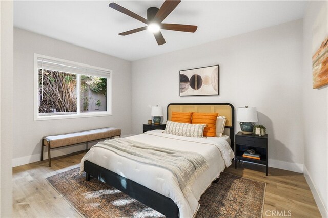 bedroom with baseboards, light wood finished floors, and ceiling fan