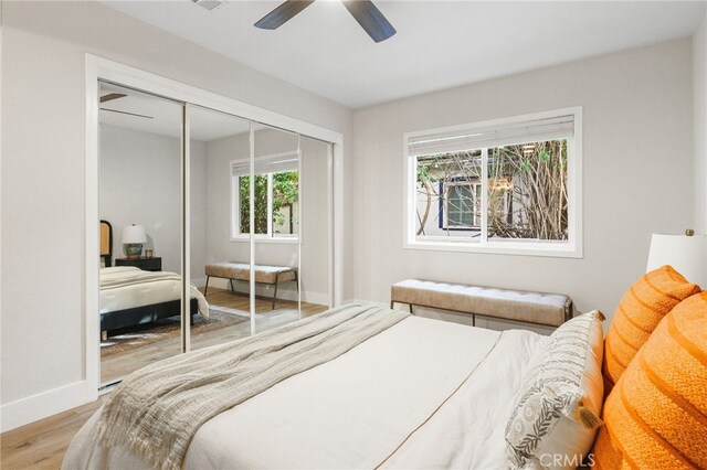 bedroom with baseboards, ceiling fan, wood finished floors, and a closet