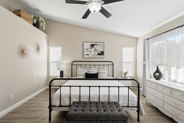 bedroom featuring baseboards, light wood-style floors, and lofted ceiling