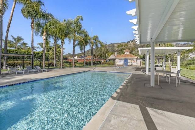 community pool featuring a patio area, a mountain view, and fence